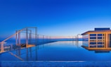 A stunning modern swimming pool with clear blue water reflecting Dubai's skyline at sunset.