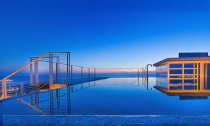 A serene shot of the rooftop infinity pool reflecting the deep blue evening sky and city lights.