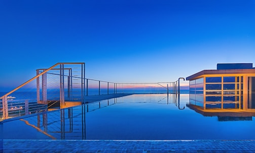 A stunning modern swimming pool with clear blue water reflecting Dubai's skyline at sunset.