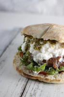 Close-up of a layered sandwich with toasted bread, fresh greens, and house-made sauce.