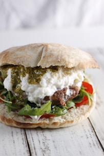 Close-up of a sandwich filled with grilled meat and chimichurri spread.