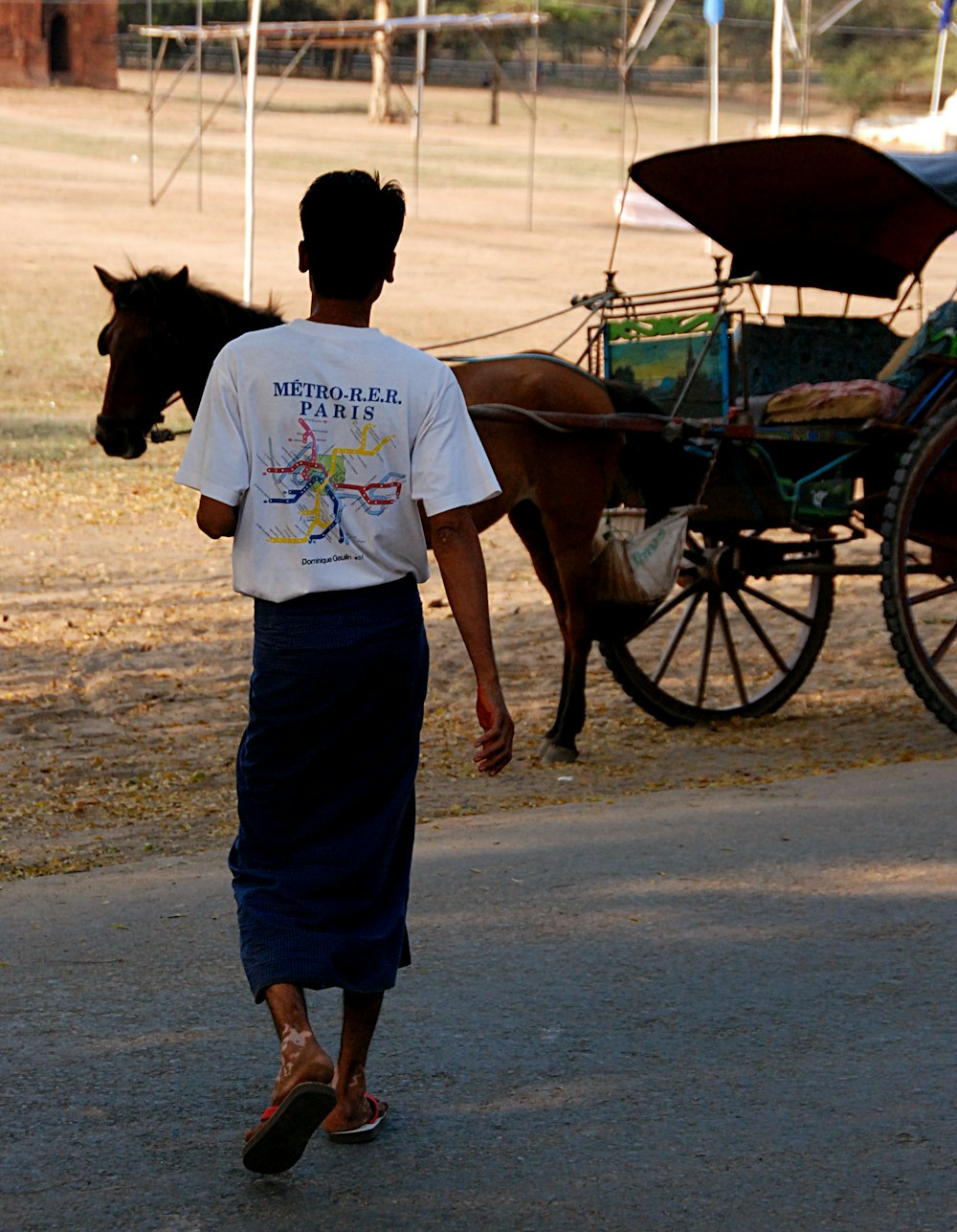 a man walking with a horse and buggy