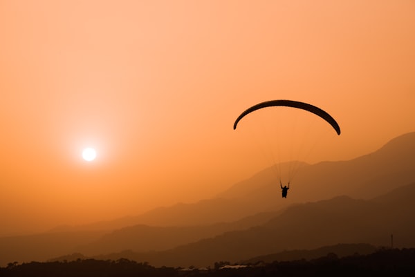 Paraglider at sunset over mountains