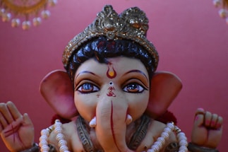 A serene image of Ganesh Ji with a gentle smile, surrounded by softly glowing rudraksha beads against a warm dark yellow background.