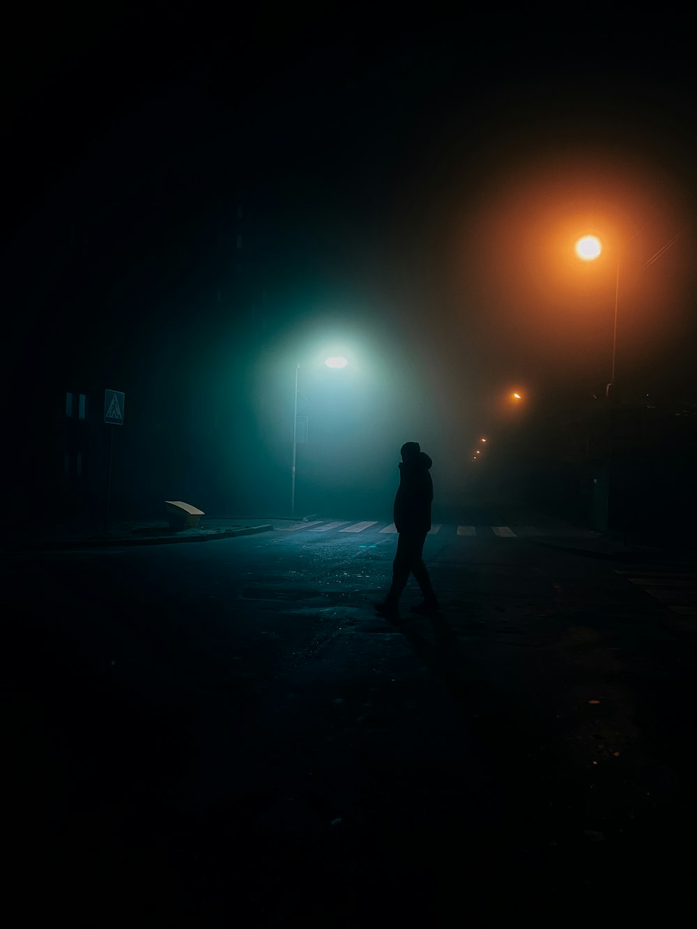 a person standing in a dark area with street lights
