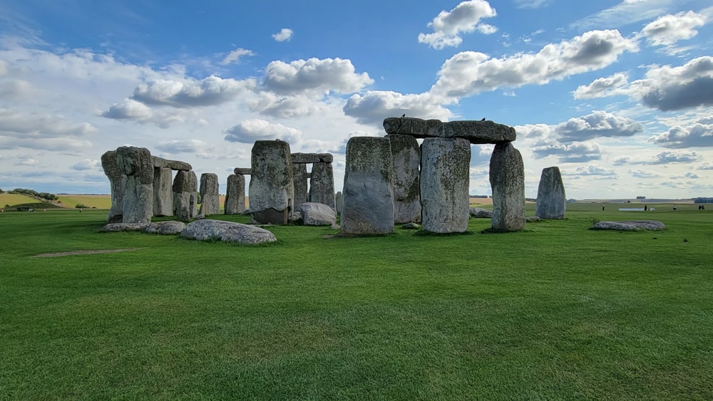 a grassy field with rocks in it with Stonehenge in the background