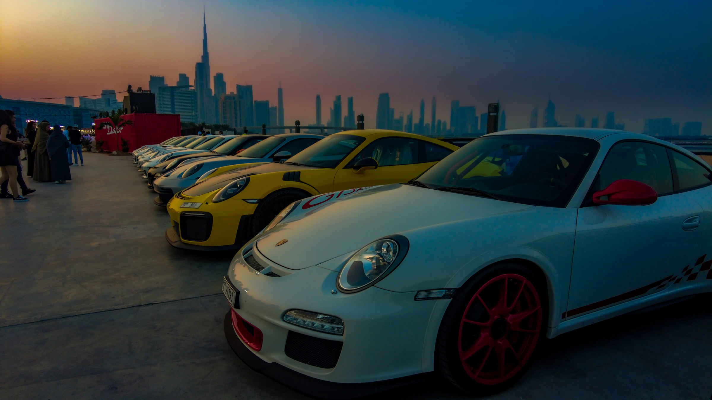 Premium cars lined up with the Dubai skyline at dusk