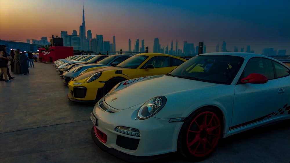 a group of cars parked on a street with a city skyline in the background