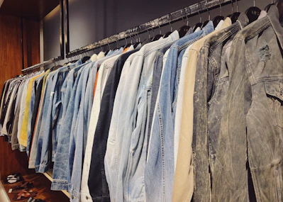 A cozy display of gently used jackets, sweaters, and scarves hanging on a rustic wooden rack.