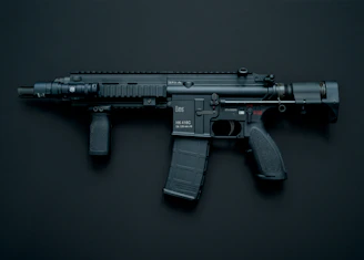 Close-up of a flashlight attached to a firearm rail, casting a bright beam in a dark setting.