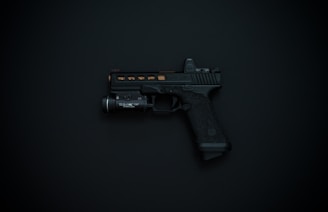 A black handgun with detailing and an attached flashlight is displayed against a dark background.