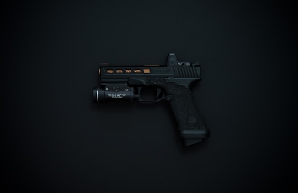 A black handgun with detailing and an attached flashlight is displayed against a dark background.