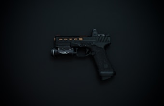 A black handgun with detailing and an attached flashlight is displayed against a dark background.