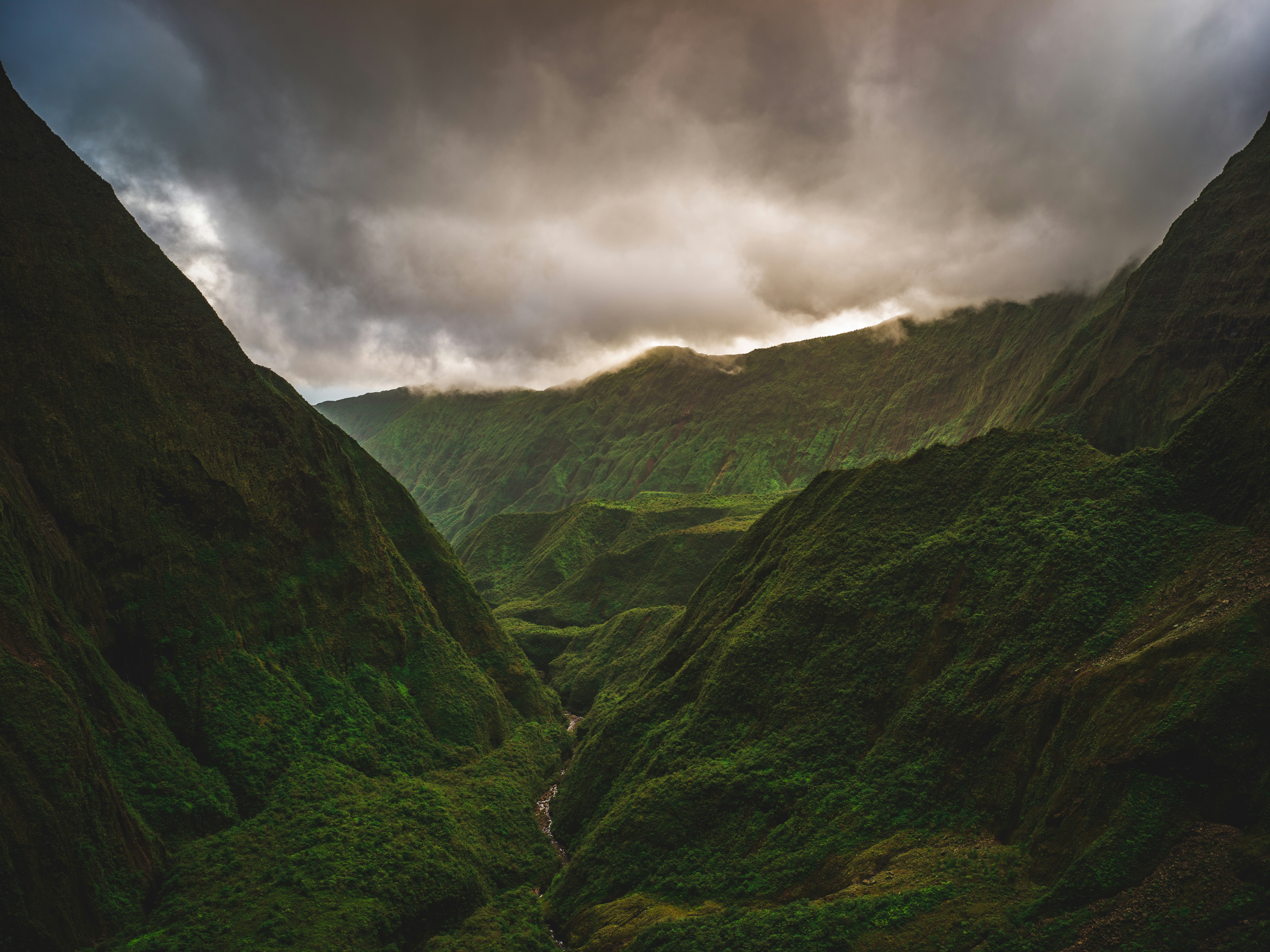 a green valley with a cloudy sky with Winnats Pass in the background