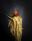 Artistic shot of spaghetti twirled around a fork with parmesan cheese sprinkled on top.