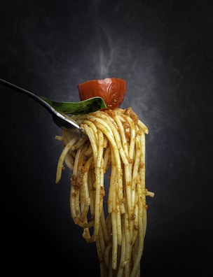 Artistic shot of spaghetti twirled around a fork with parmesan cheese sprinkled on top.