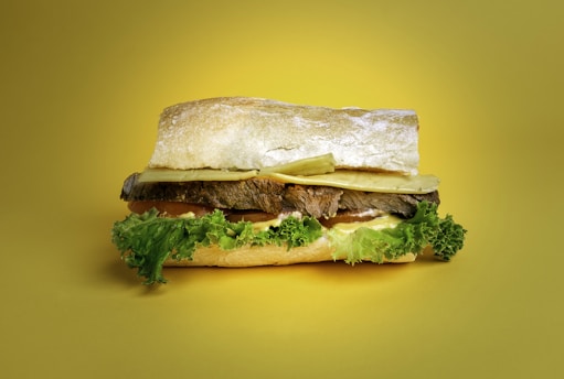 a sandwich with lettuce and meat on a wooden surface