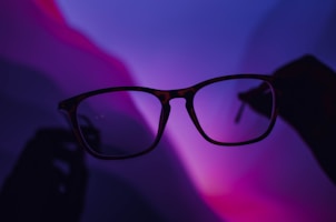 A set of LED-lit smart glasses casting a soft purple glow in a dark room