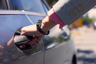 A professional chauffeur opening a car door for a business traveler.