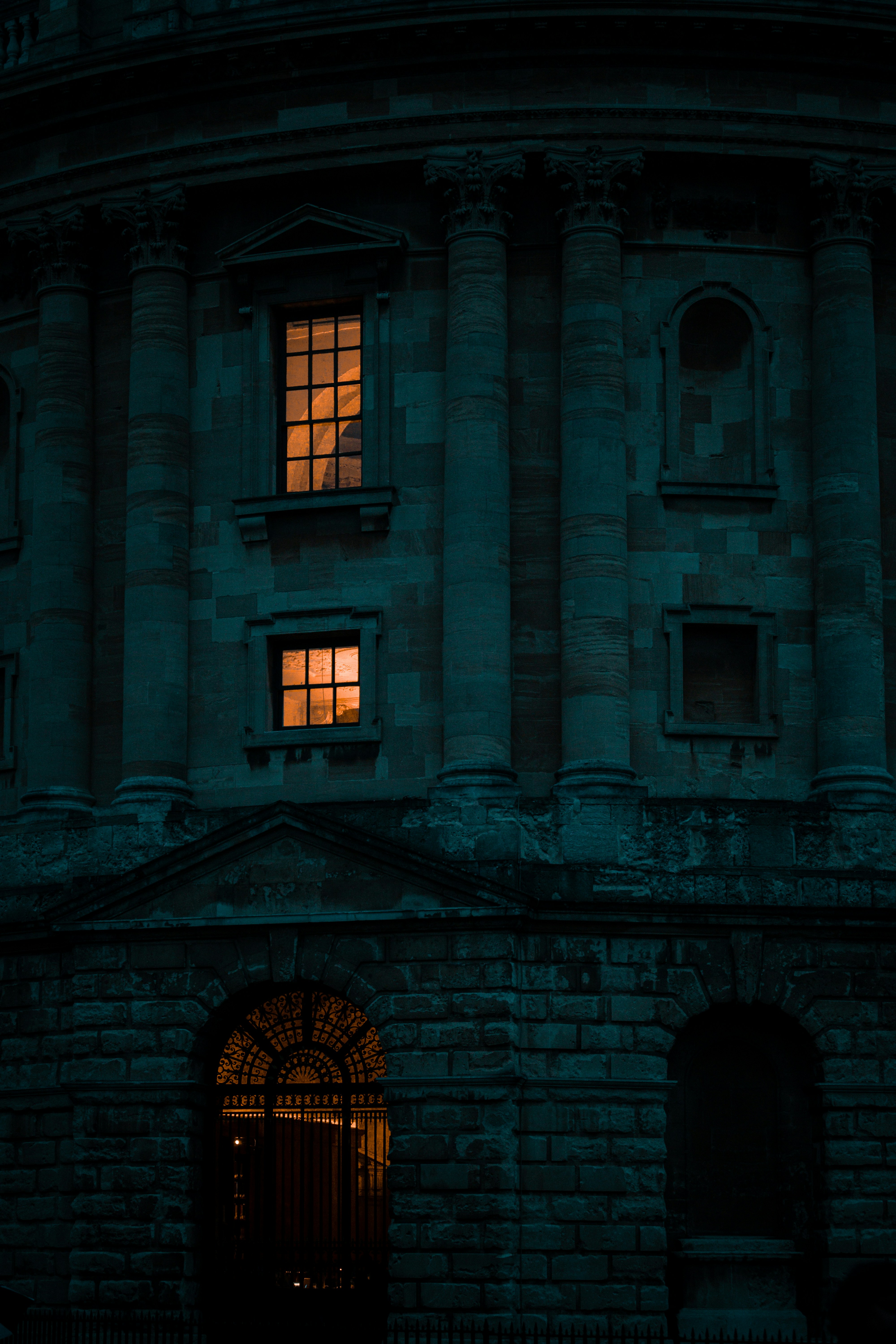 Grand hotel exterior at night, warm windows glowing, dark sky, ornate stone facade