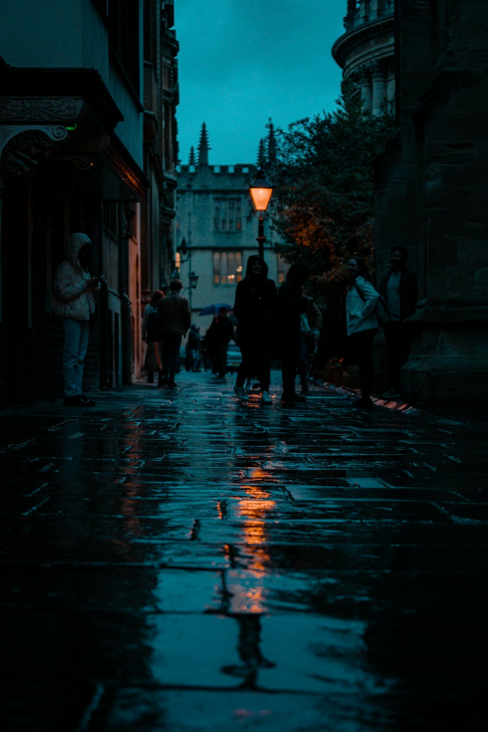 a group of people standing on a wet sidewalk