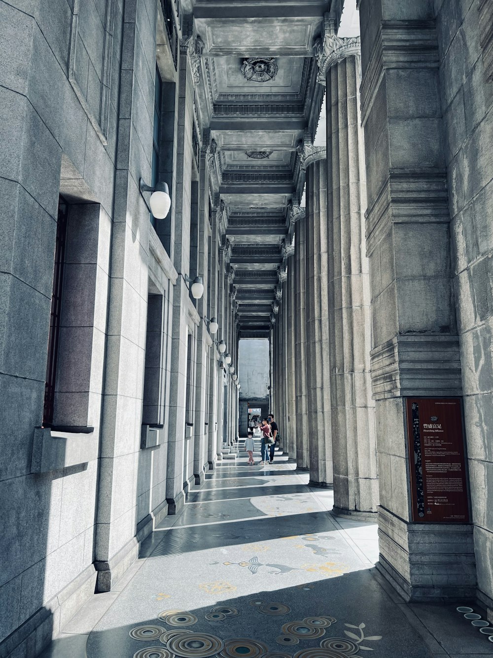 a couple of people walking down a hallway between two buildings