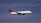 An airplane with the logo of Air Canada is flying in a clear sky. The jet is positioned slightly to the right, and its landing gear is deployed.