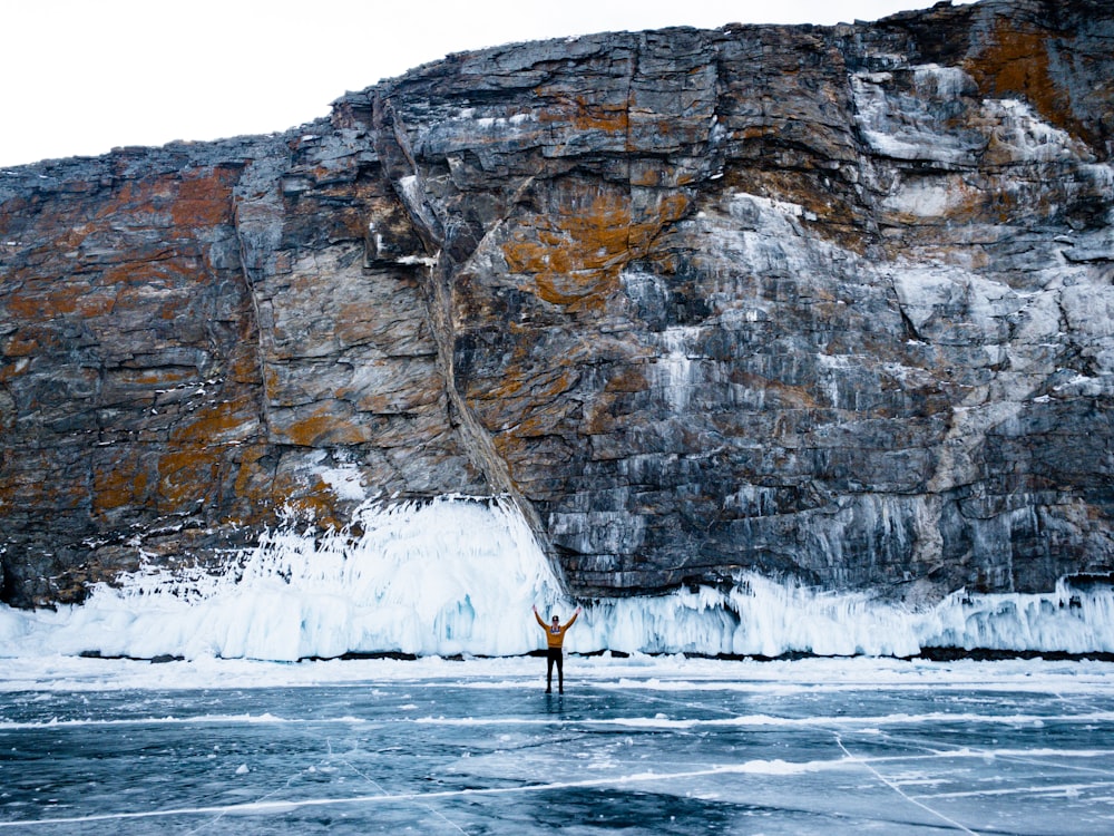 a person standing in front of a large rock cliff