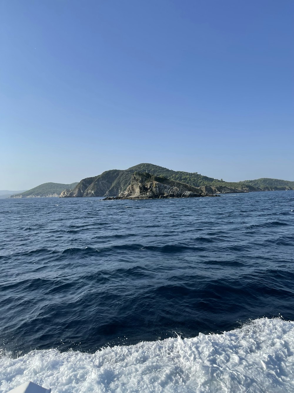 a body of water with a rocky island in the distance