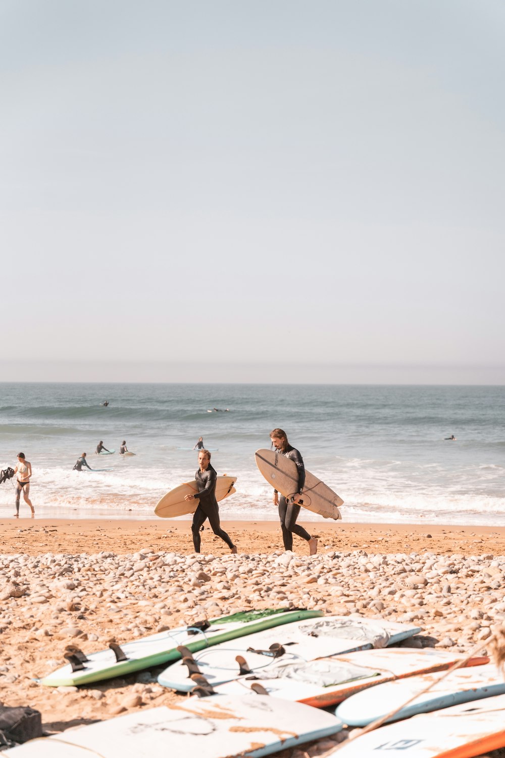 surfeurs portant leurs planches sur la plage