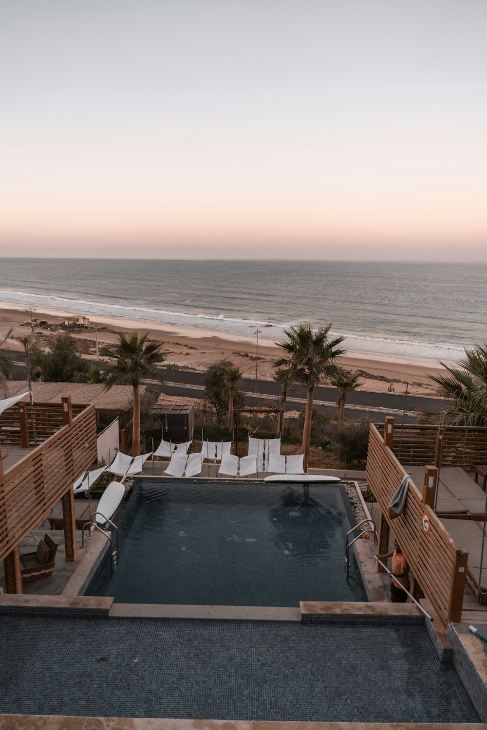 uma piscina com cadeiras em torno dele por uma praia