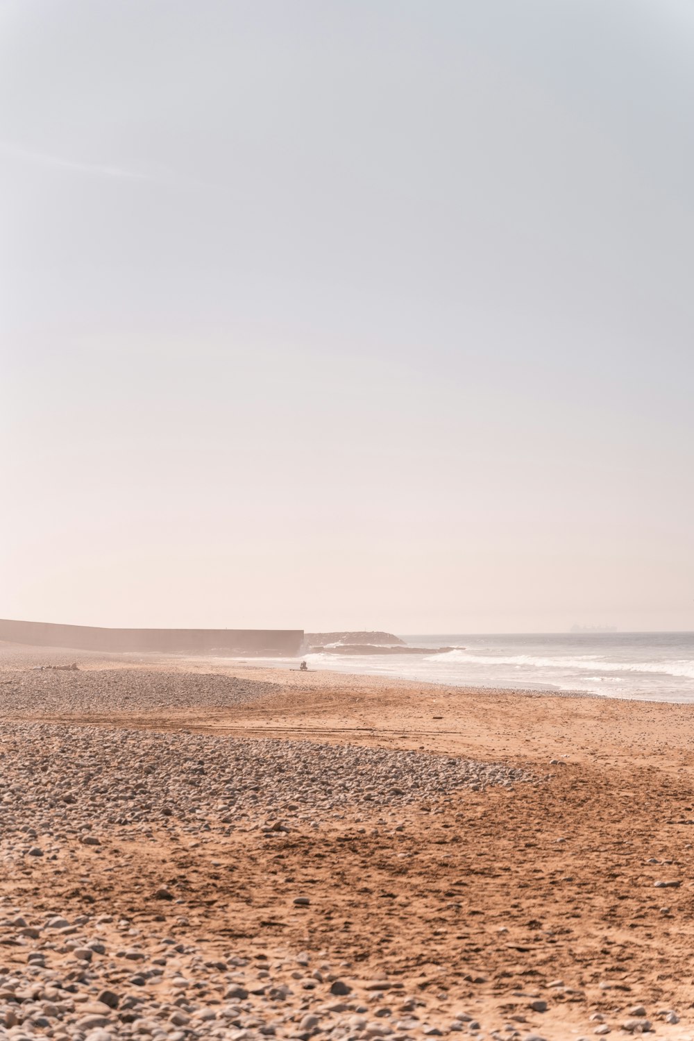 Una playa de arena con un cuerpo de agua en la distancia