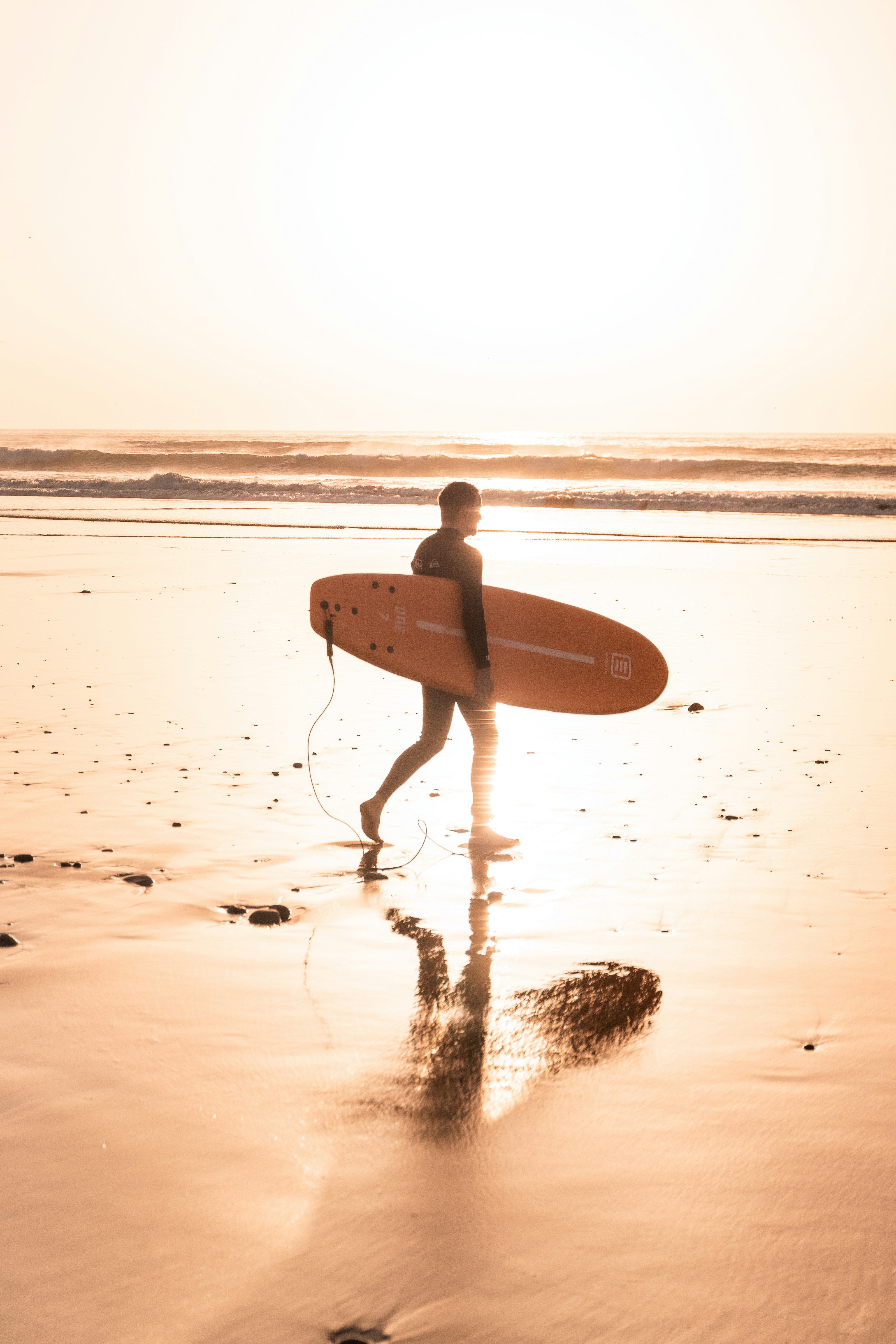 A man carrying a surfboard on a beach in Morocco