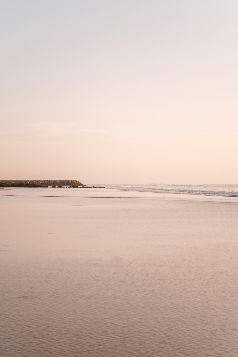 uma praia com uma pequena ilha à distância