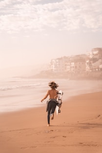 a person carrying a dog on a beach