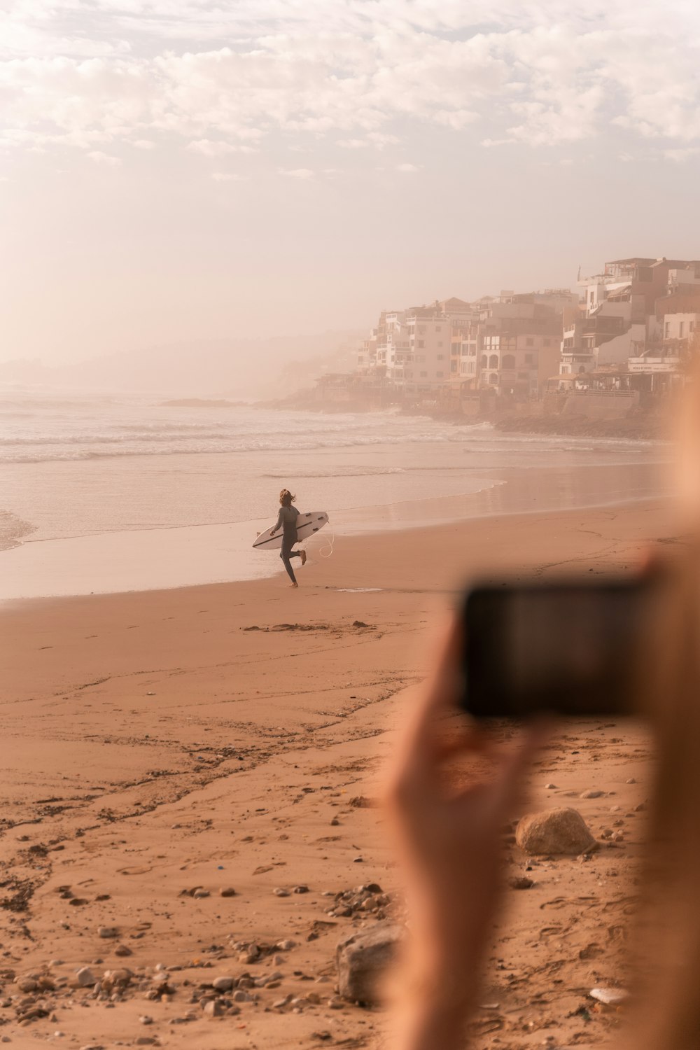 a person holds a surfboard on a beach