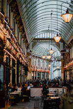a large room with many people sitting at tables and chairs with Leadenhall Market in the background