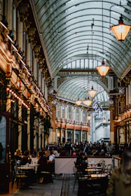 a large room with many people sitting at tables and chairs with Leadenhall Market in the background