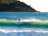 A surfer catching a perfect wave against a backdrop of lush green hills in Catanduanes.
