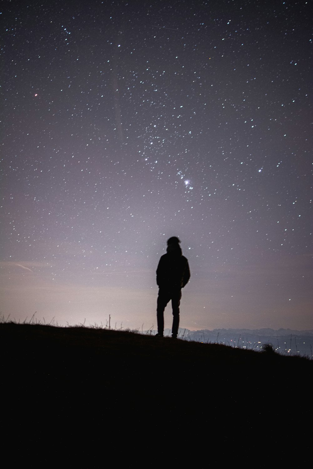 a person standing on a hill looking at the stars in the sky