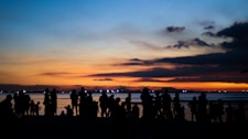 a group of people standing on a beach at sunset
