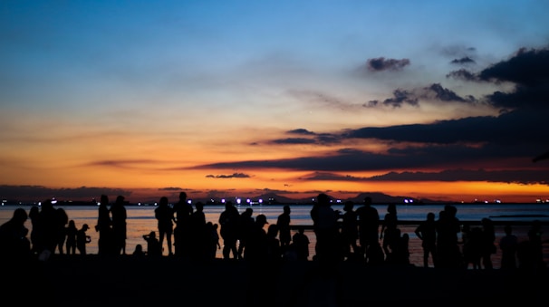 a group of people standing on a beach at sunset