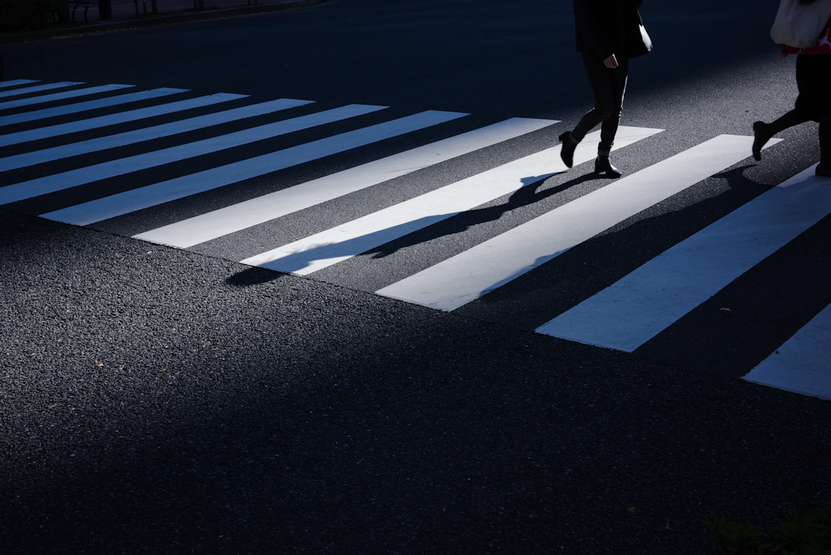 A person stepping onto a zebra crossing at night, lit by headlights