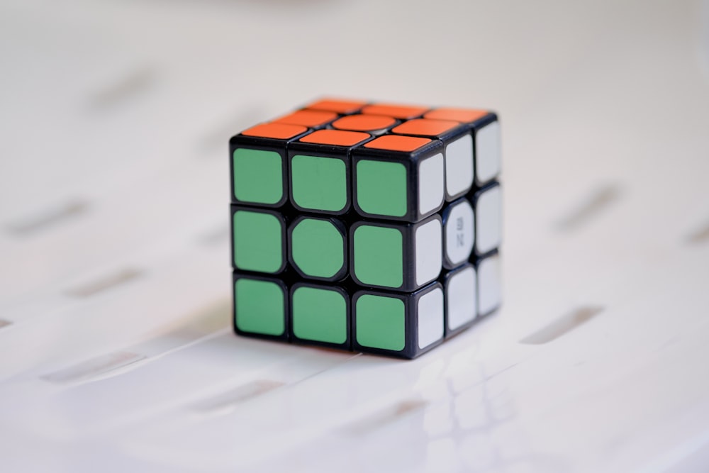 a cube with a green and orange design on a white surface