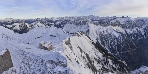 A scenic view of snow-covered mountains with a cozy lodge in the foreground.
