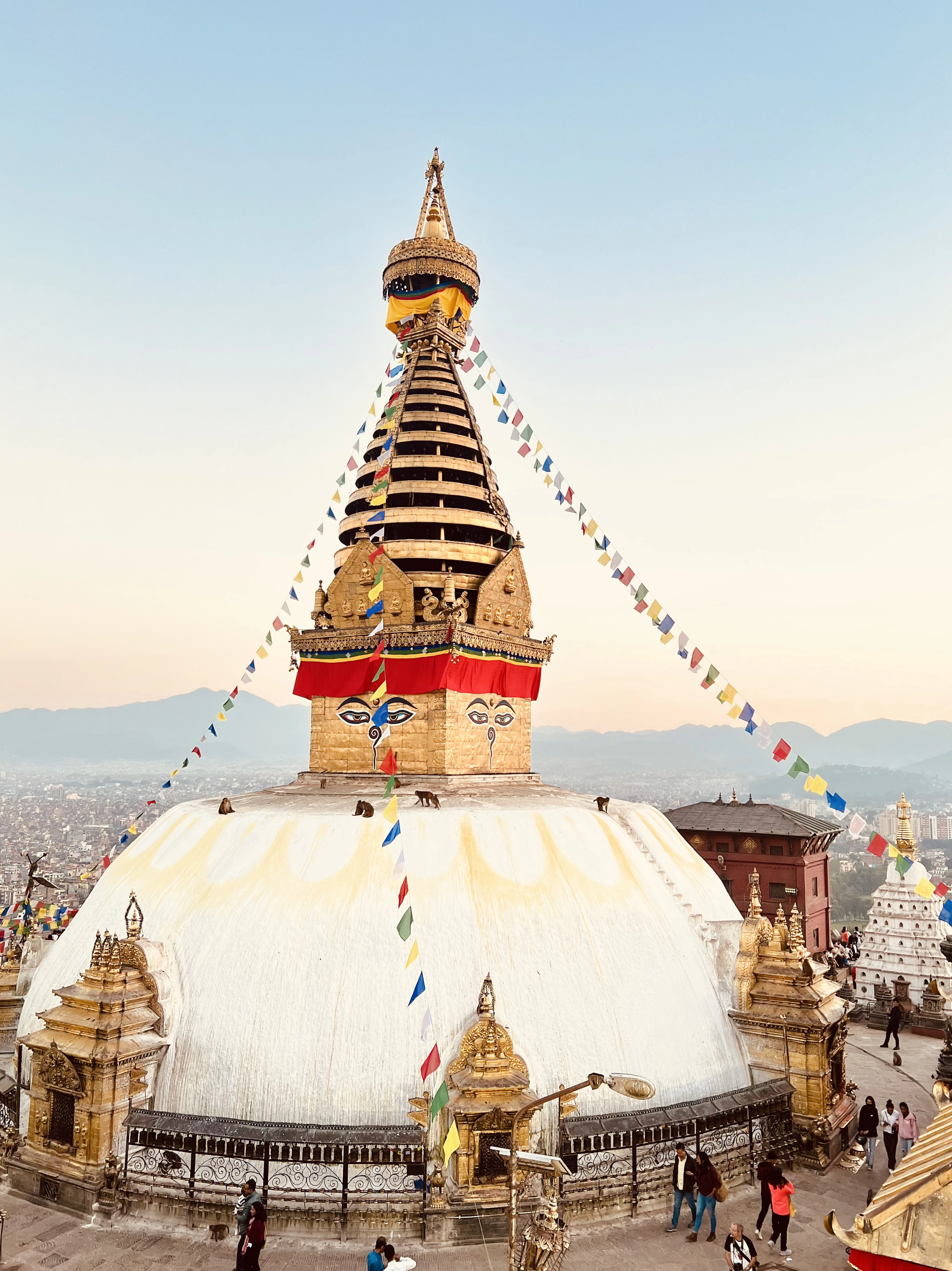 Swayambhunath Stupa's gilded spire and cascading prayer flags catch the last light above the valley.