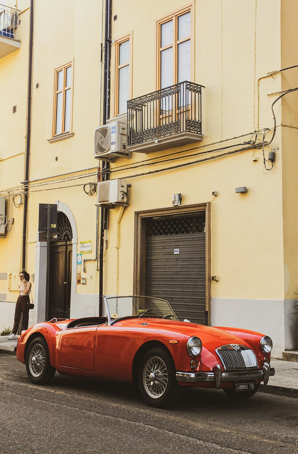 um carro esportivo vermelho estacionado na lateral de uma rua