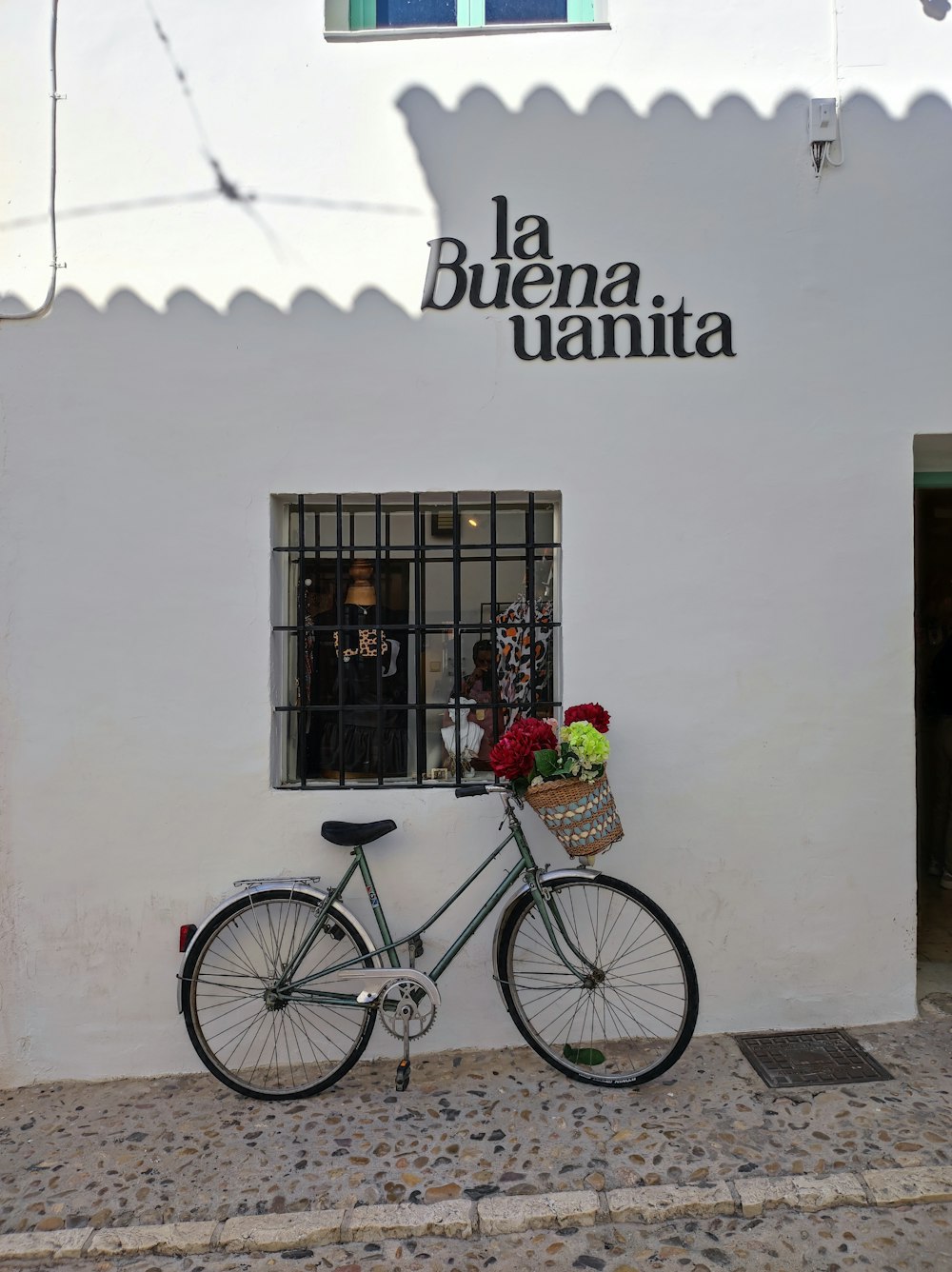 a bicycle parked in front of a building with a basket of flowers