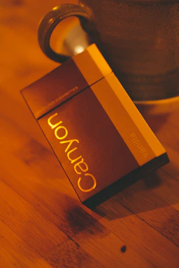 Close-up of a sleek pack of cigarettes resting on a wooden table with soft natural light highlighting the details.