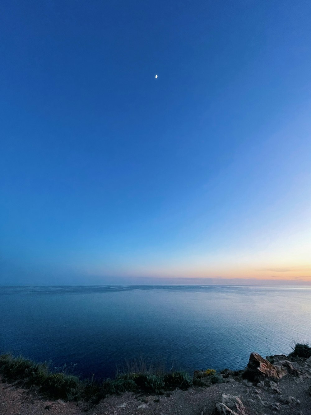 a body of water with a moon in the sky